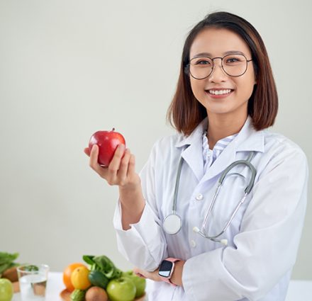 Nutritionist desk with healthy fruits, juice and measuring tape. Dietitian working on diet plan at office, smiling at camera. Weight loss and right nutrition concept การดูแลโภชนาการจากนักโภชนาการ บ้านลลิสา Nursing Home